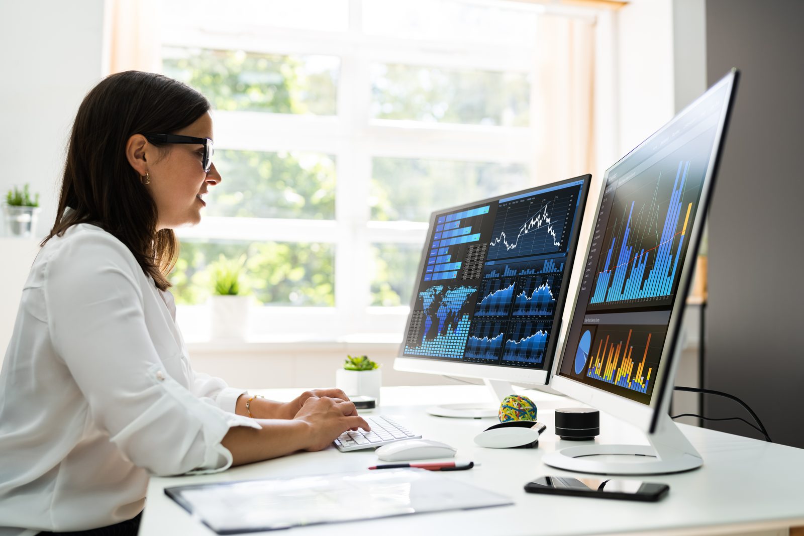 Analystin arbeitet mit Power BI Dashboards auf zwei Monitoren